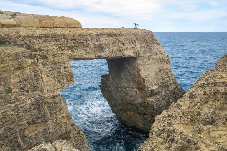 Climbers stand on the rock arch Wied il-Mielah