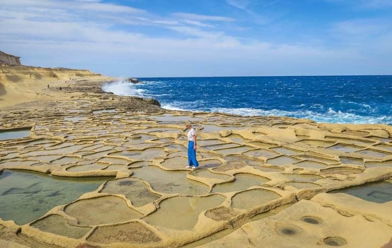 Woman walks over the salt pans of Gozo filled with seawater