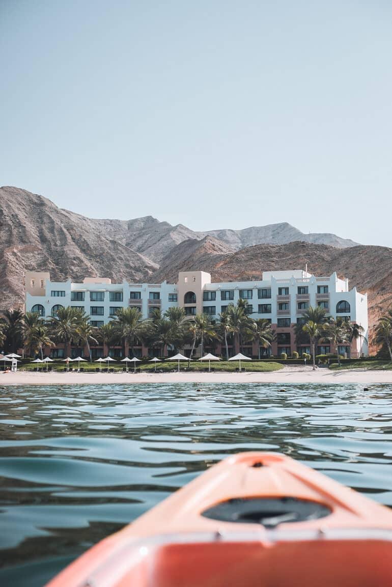 En el mar frente al complejo hotelero Shangri La Al Bandar en Omán, un kayak naranja se dirige hacia la playa de arena.