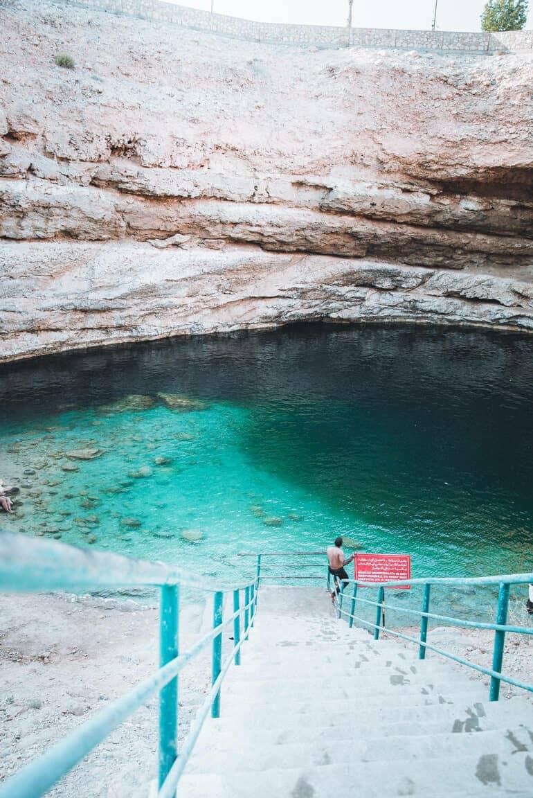 La empinada escalera del Bimah Sinkhole en Omán lleva a los visitantes a una laguna de color azul verdoso.