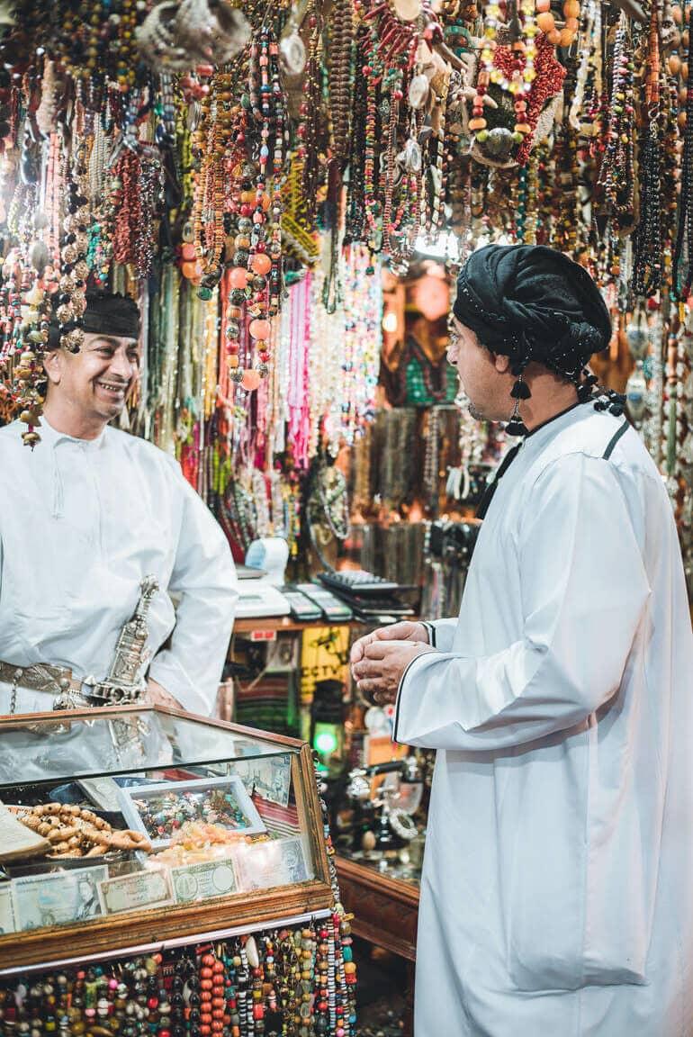 En una tienda adornada con joyas en el mercado del Zoco de Mutrah en Omán, dos hombres locales conversan.