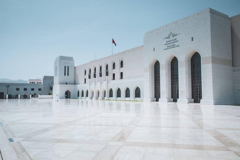 La impresionante Casa de la Ópera Real con sus muchos arcos y columnas en Mascate, Omán, está equipada con una enorme plaza con grandes adoquines blancos brillantes.