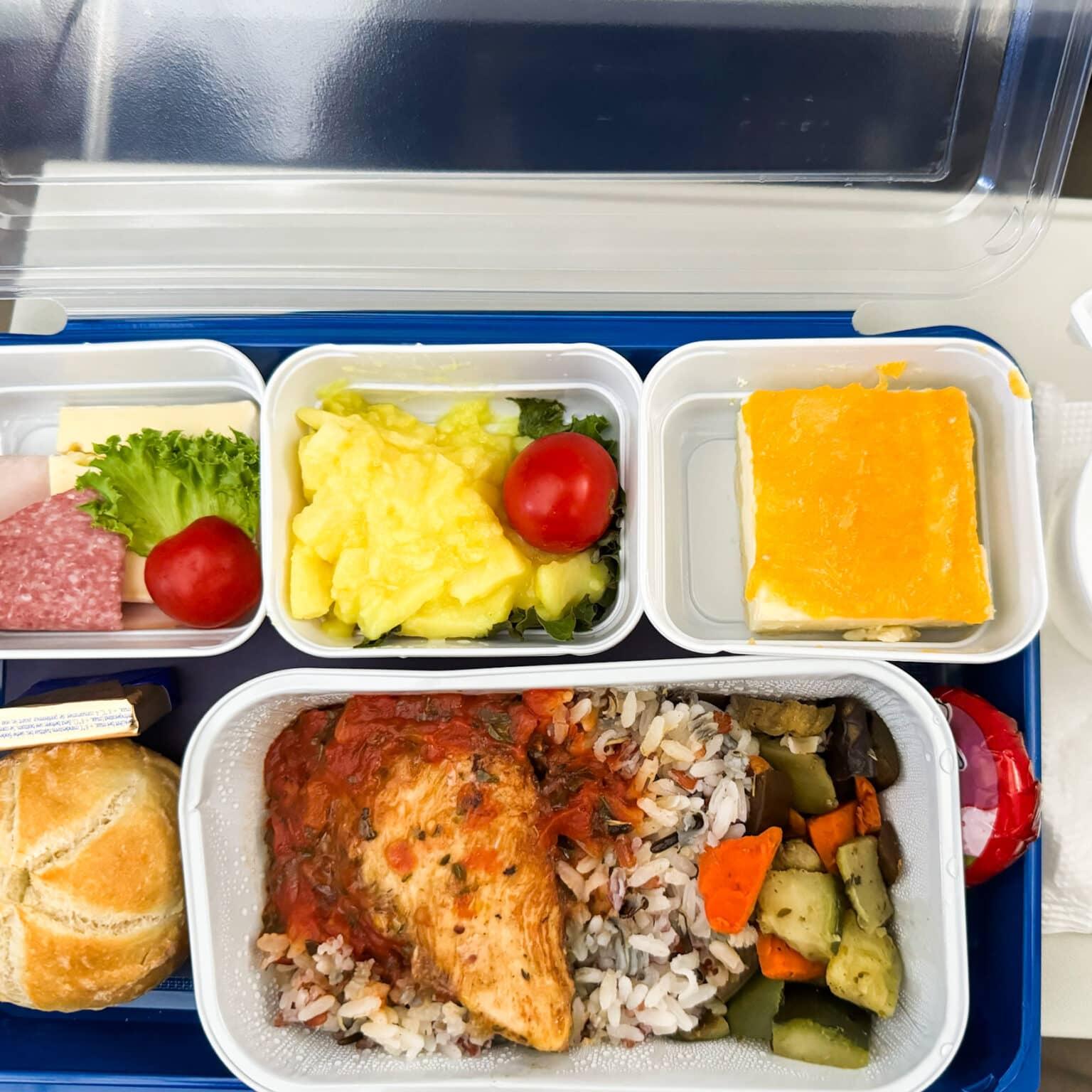 El menú a bordo de Uzbekistan Airways con arroz, verduras, carne, un bollo, embutido y queso, ensalada de patata y un trozo de pastel.