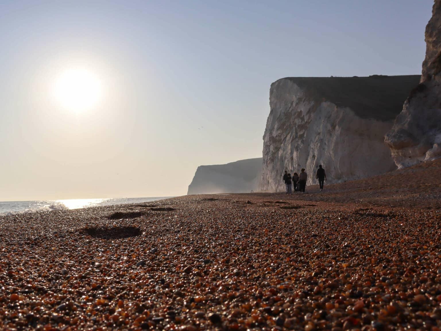 Unas cuantas personas caminan por la playa de piedras Durdle Door-Beach en el sur de Inglaterra.