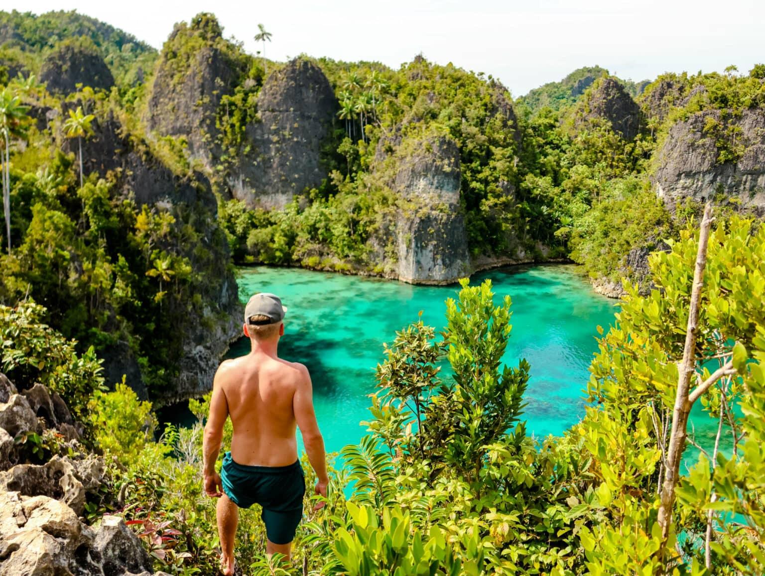 Blogger Tom standing on a cliff, looking out over the sea at the rocky coast of Star Lagoon in Raja Ampat.