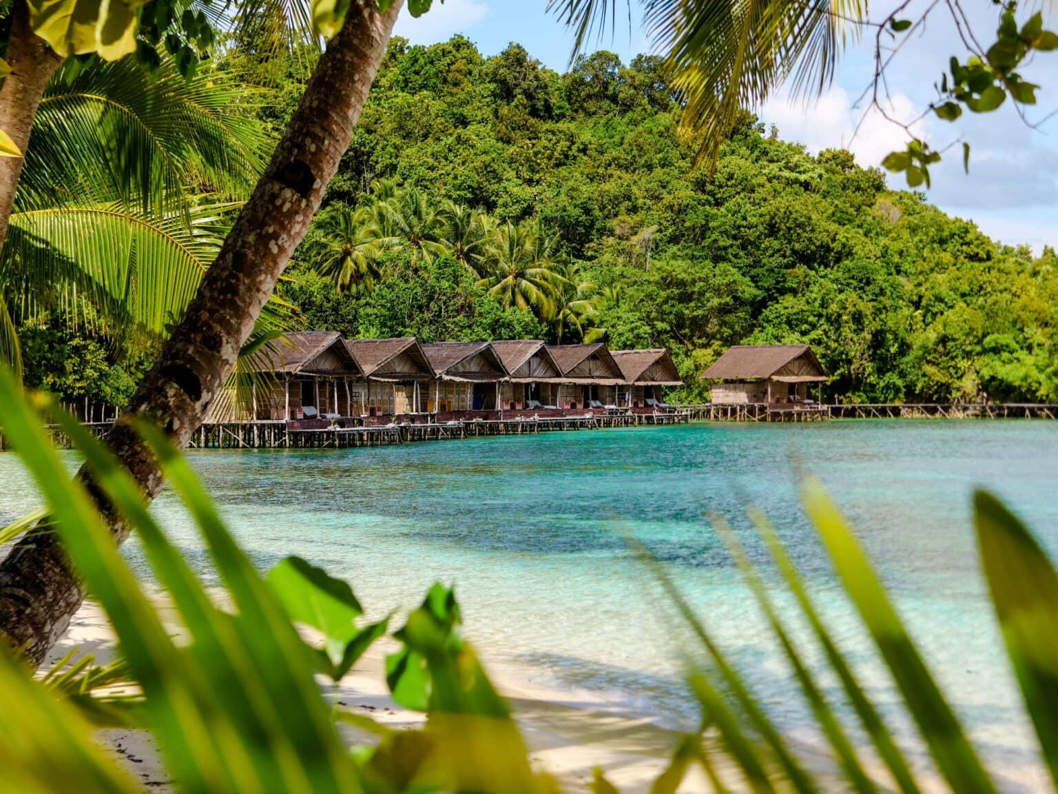 Wooden cabins line the turquoise coastline of Raja Ampat.