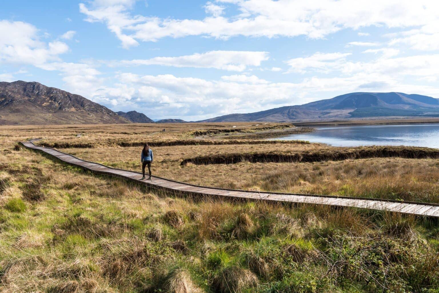 Biggi camina por la pasarela de Claggan Mountain Coastal Trail a través de un paisaje imponente