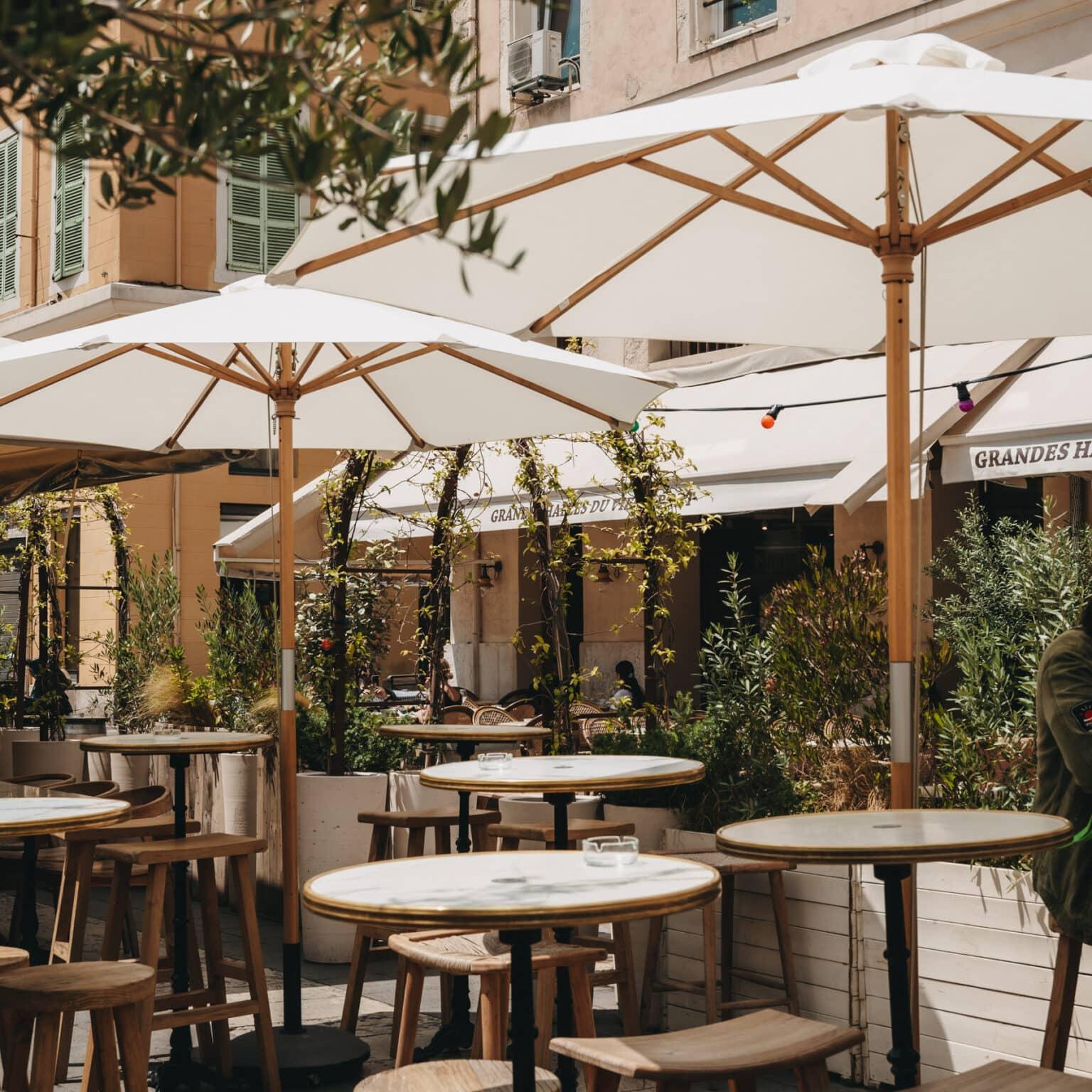 The outdoor terrace with white umbrellas of the restaurant Grandes Halles du Vieux Port.