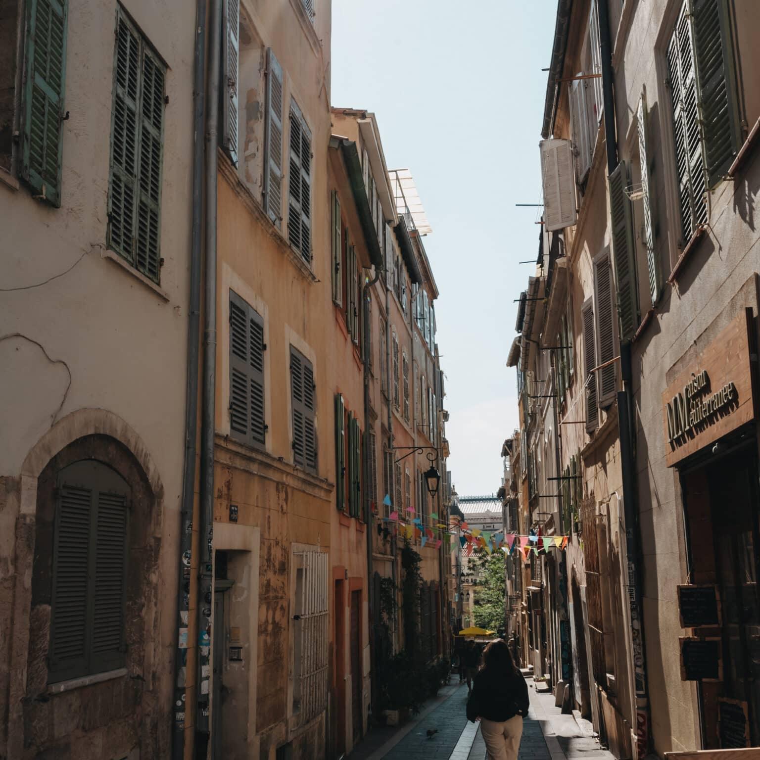 An old alley with colorful flags between the houses in the Le Panier district.