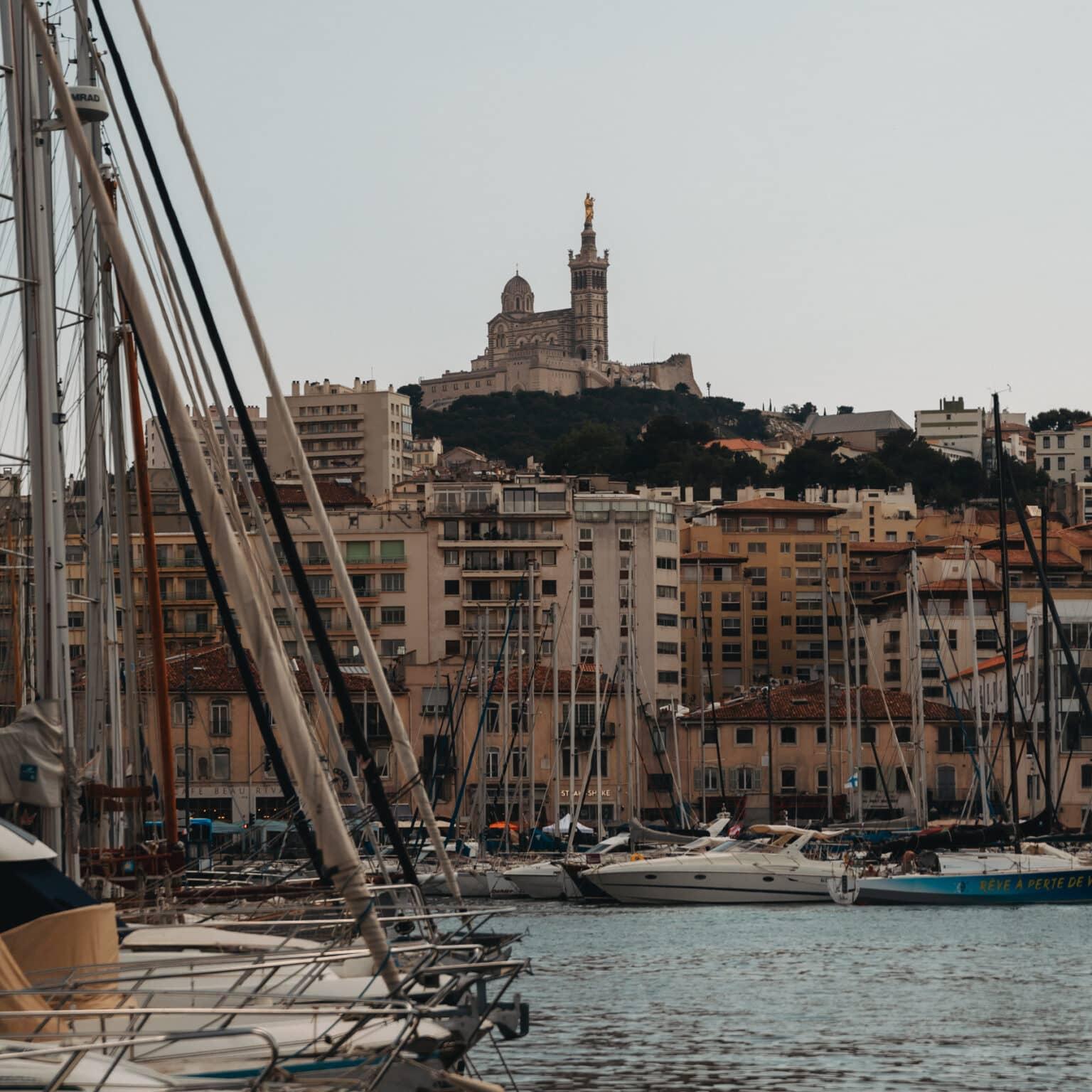 The port of Marseille with many sailboats and colorful houses in the background.