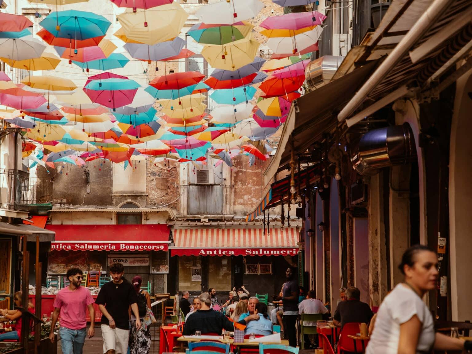 A colorful alley in Catania decorated with umbrellas.