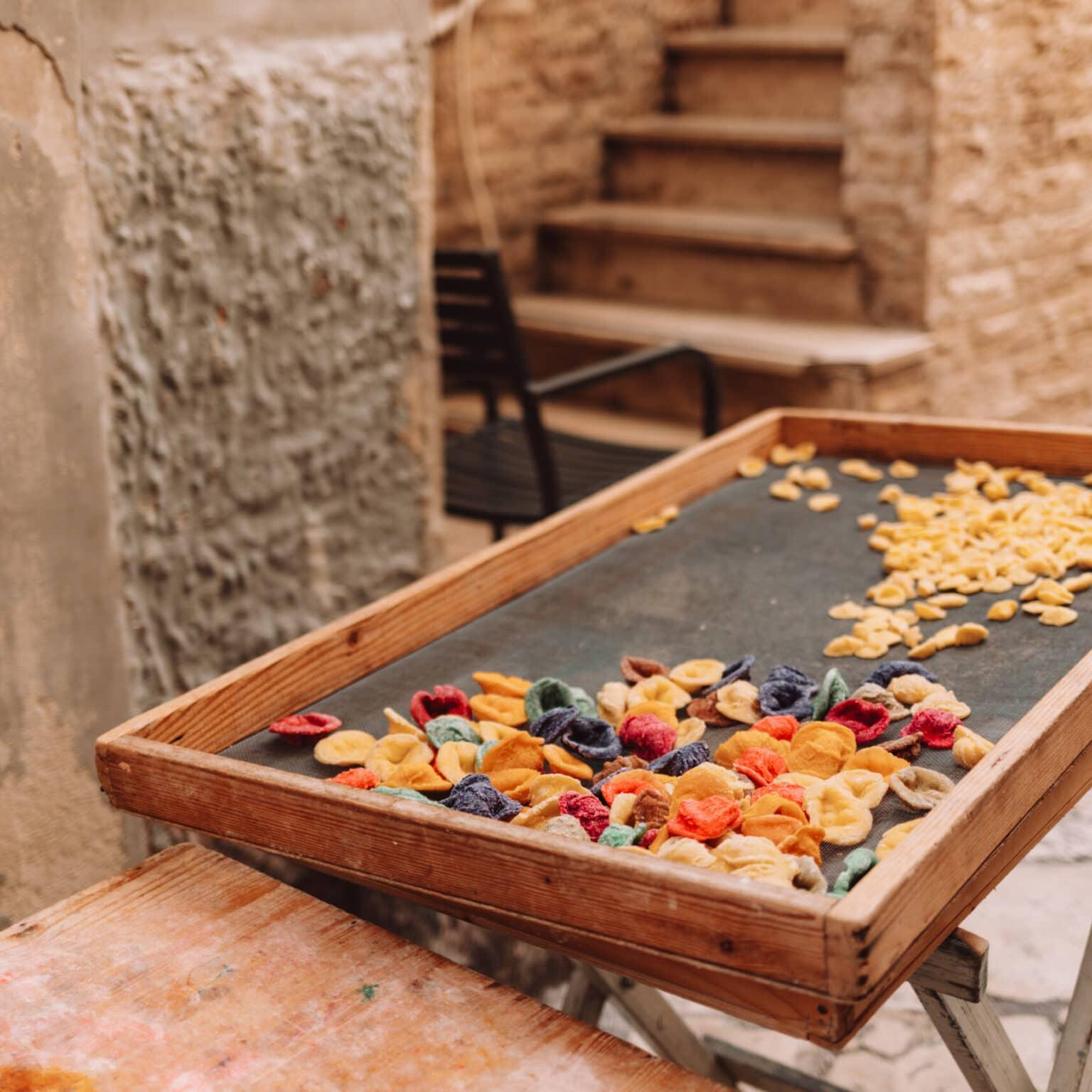 Colorful pasta on a tray in front of a restaurant.