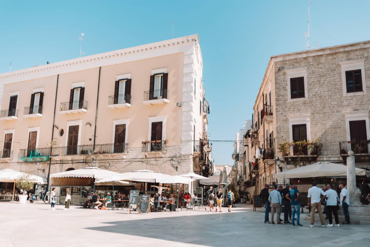 A bright square in Bari with many restaurants and people.