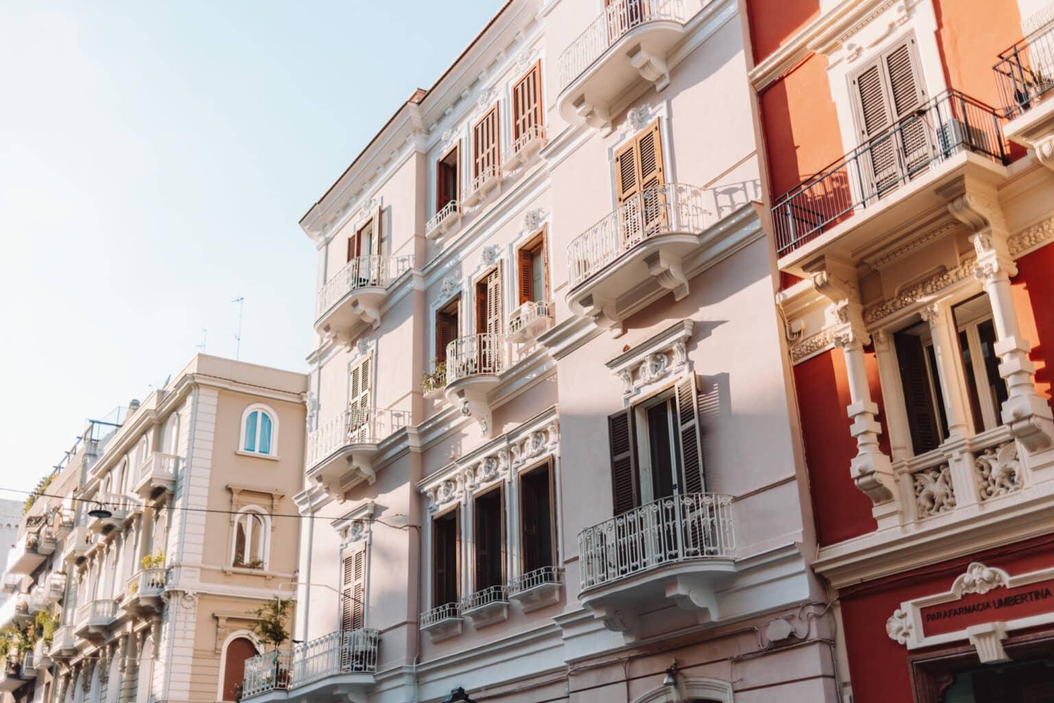 A pink house facade with ornate windows and balconies in Bari.