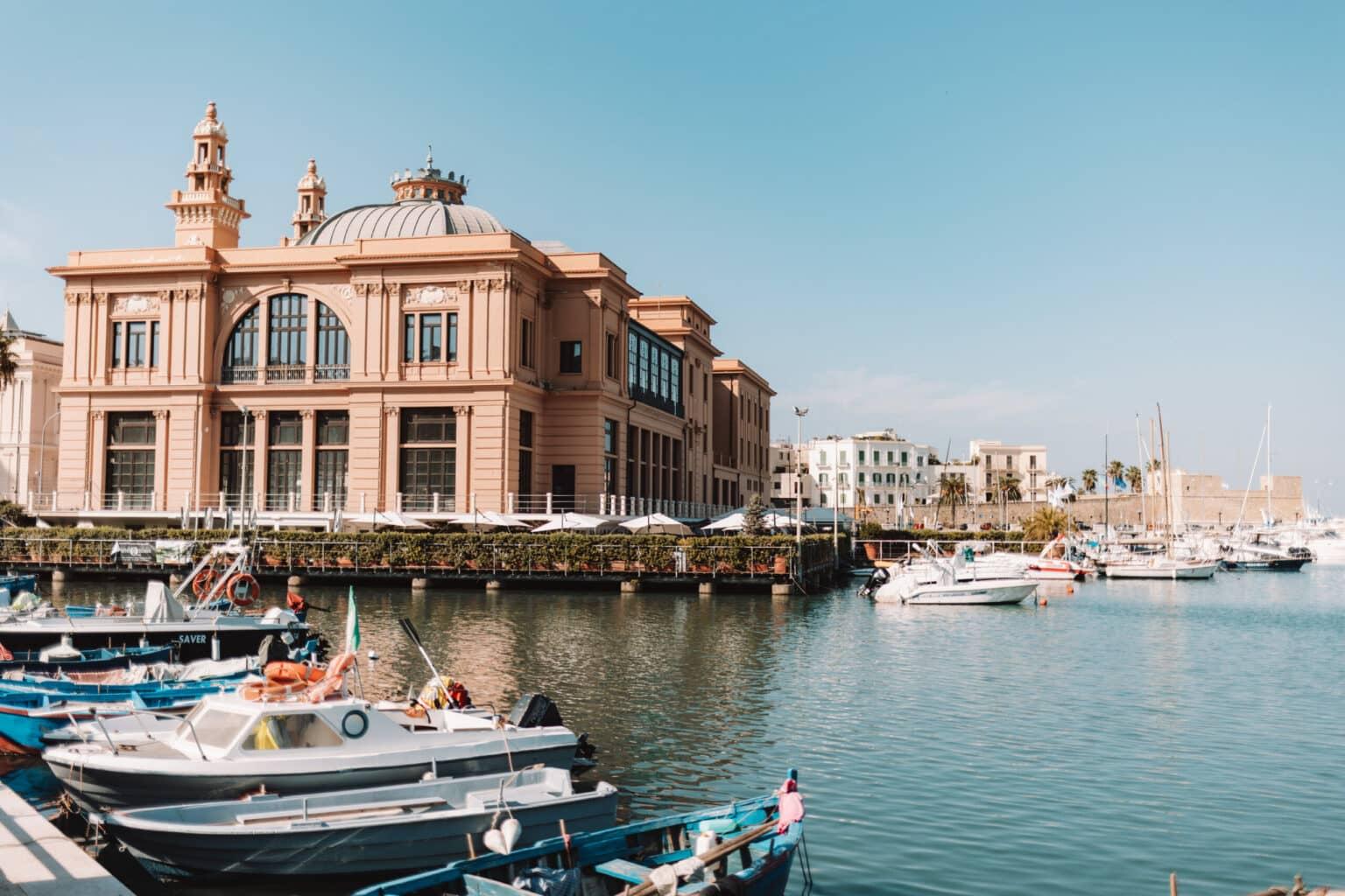 View of the harbor with many boats and the former theater of Bari in the background.