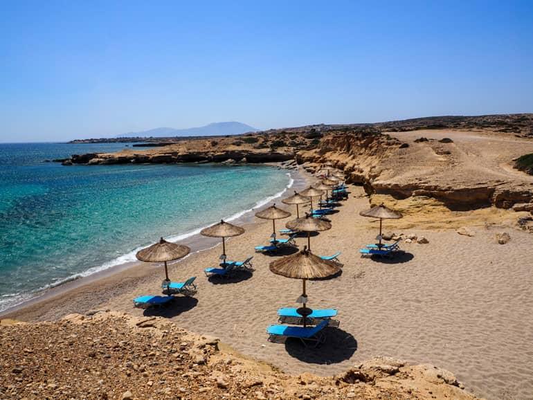 At the beautiful Michalioú Kipos Beach, straw umbrellas and blue sun loungers adorn the picturesque view of the sea.