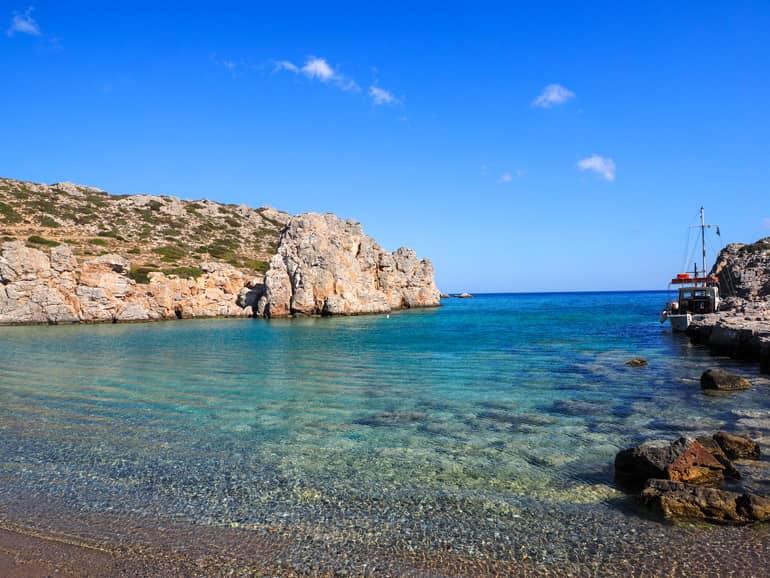 Leaning against a rock formation in the secluded Alimoúnta Bay in Karpathos, a small sailboat has taken a break.