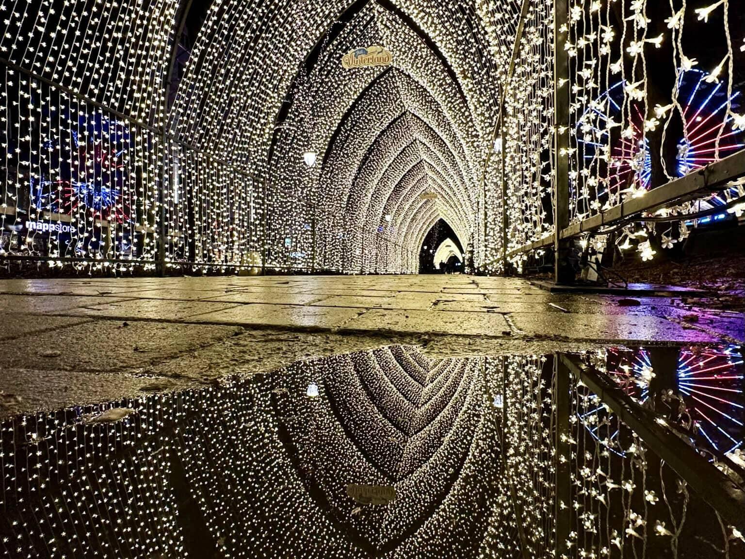 The light tunnel made of many white glowing light strings at the Christmas market in Oslo at night.
