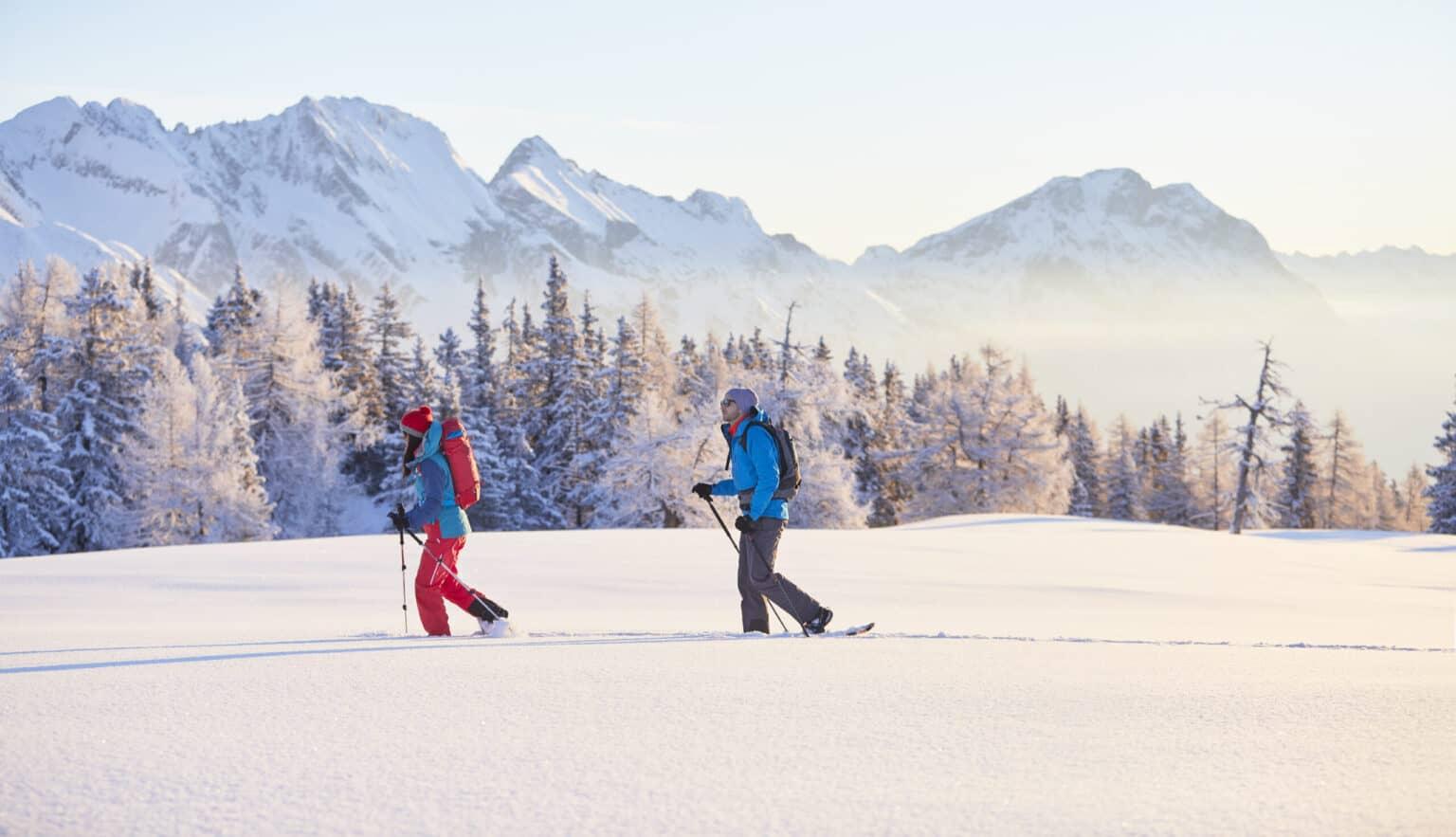 A woman and man snowshoeing in the mountains.