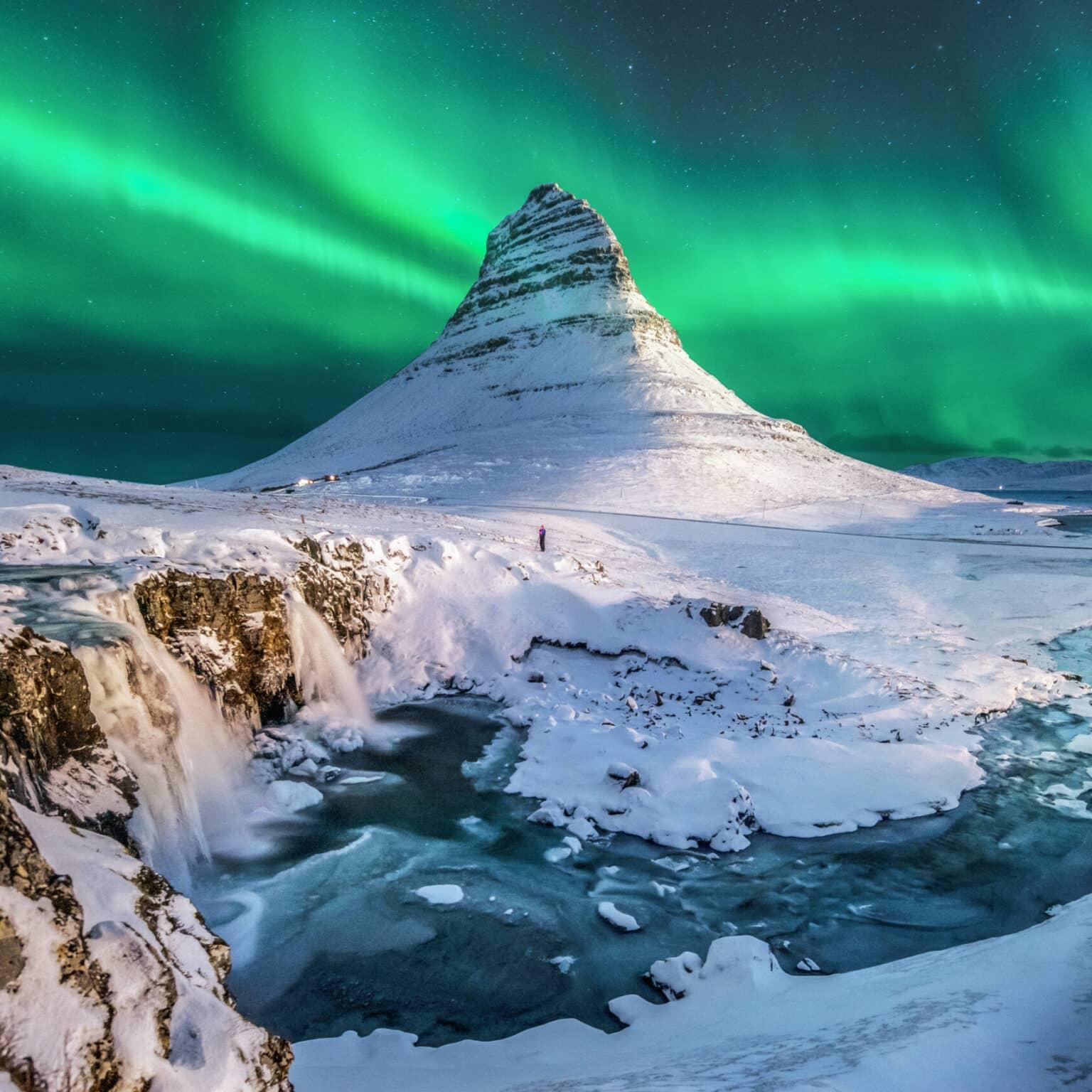 Northern lights bathe the sky over the glacier lagoon Jökulsárlón in Iceland in bright green.