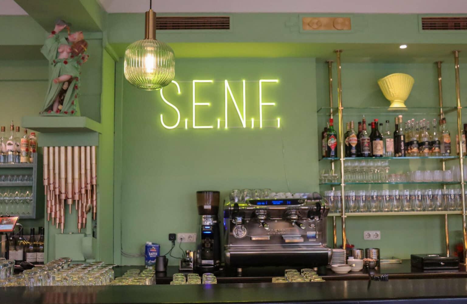The Munich Cafe Fesch glows with neon green signage reading S.E.N.F.