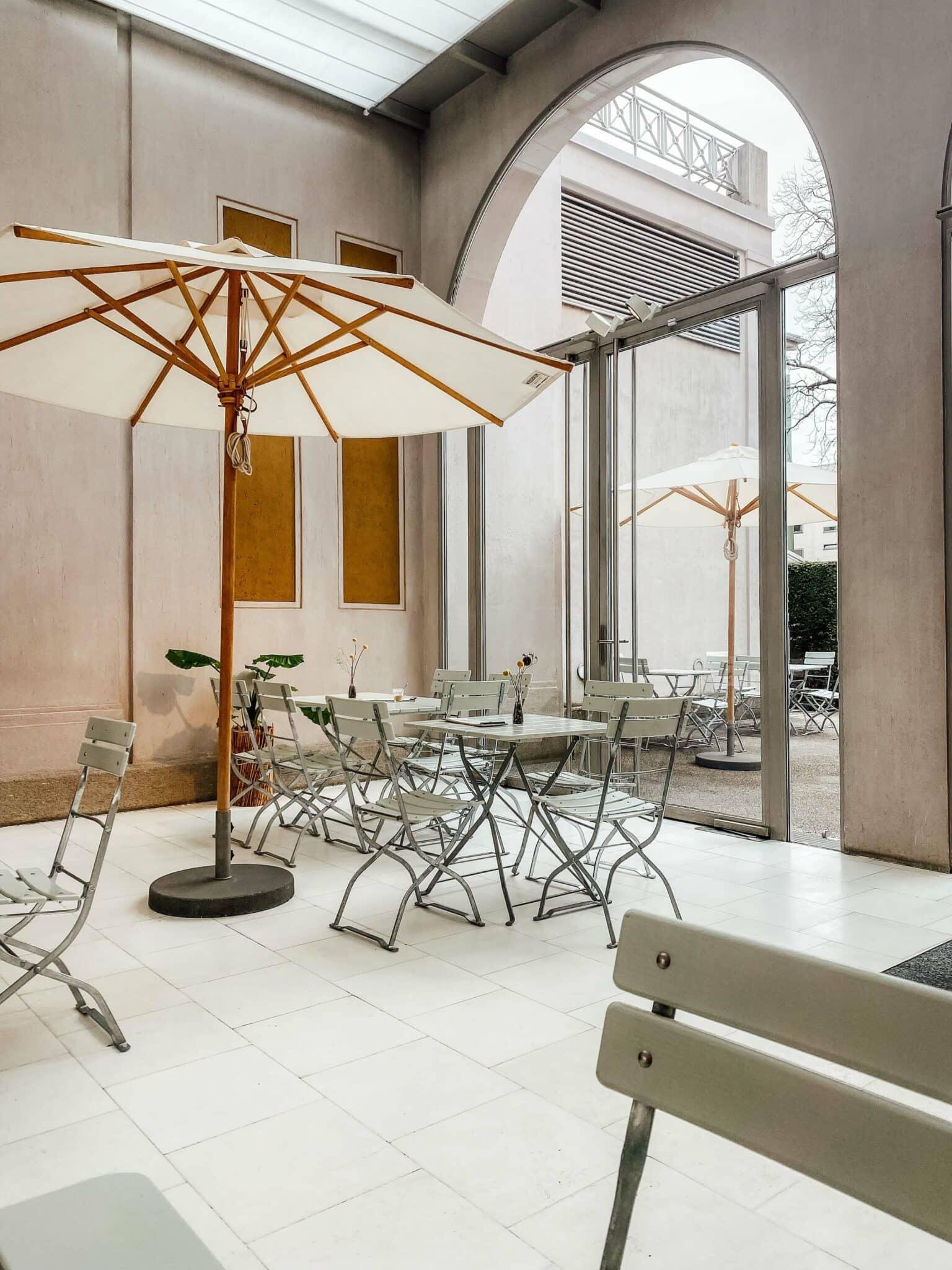 White tables and wooden chairs in the Café of the Villa Stuck in Munich.