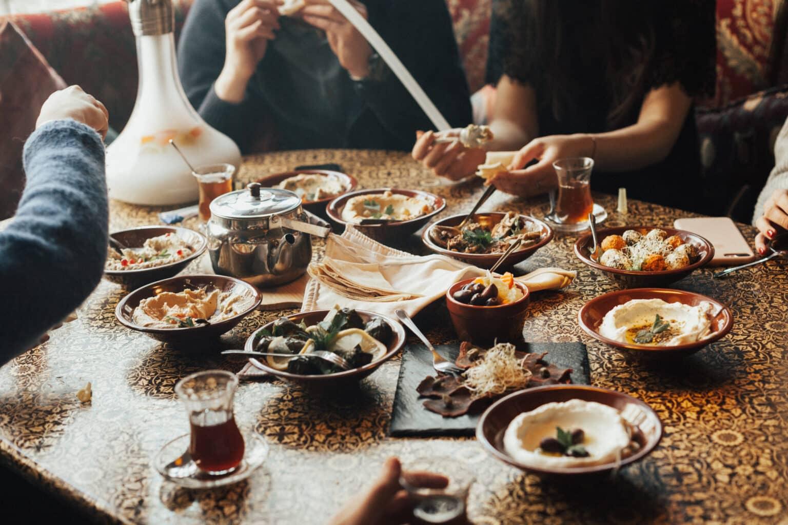 A young group of people sit together, drinking tea and eating mezze.