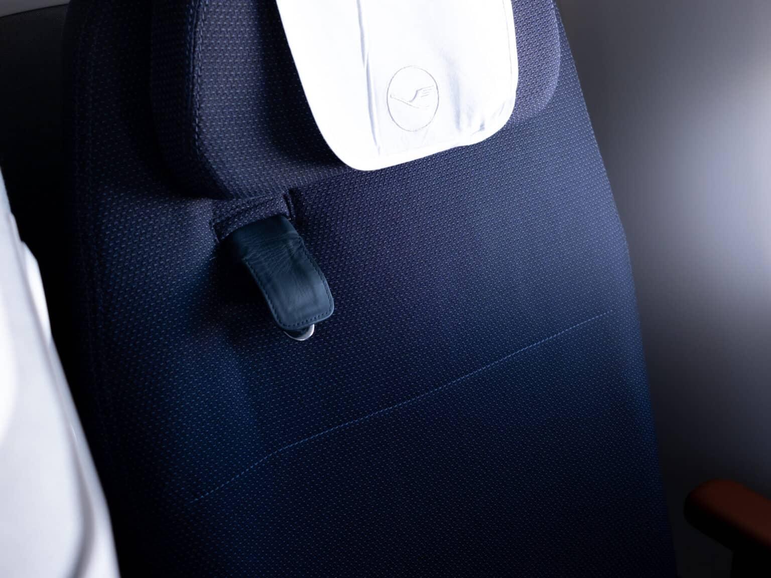 A seat in the Lufthansa Allegris Business Class with a shoulder strap.