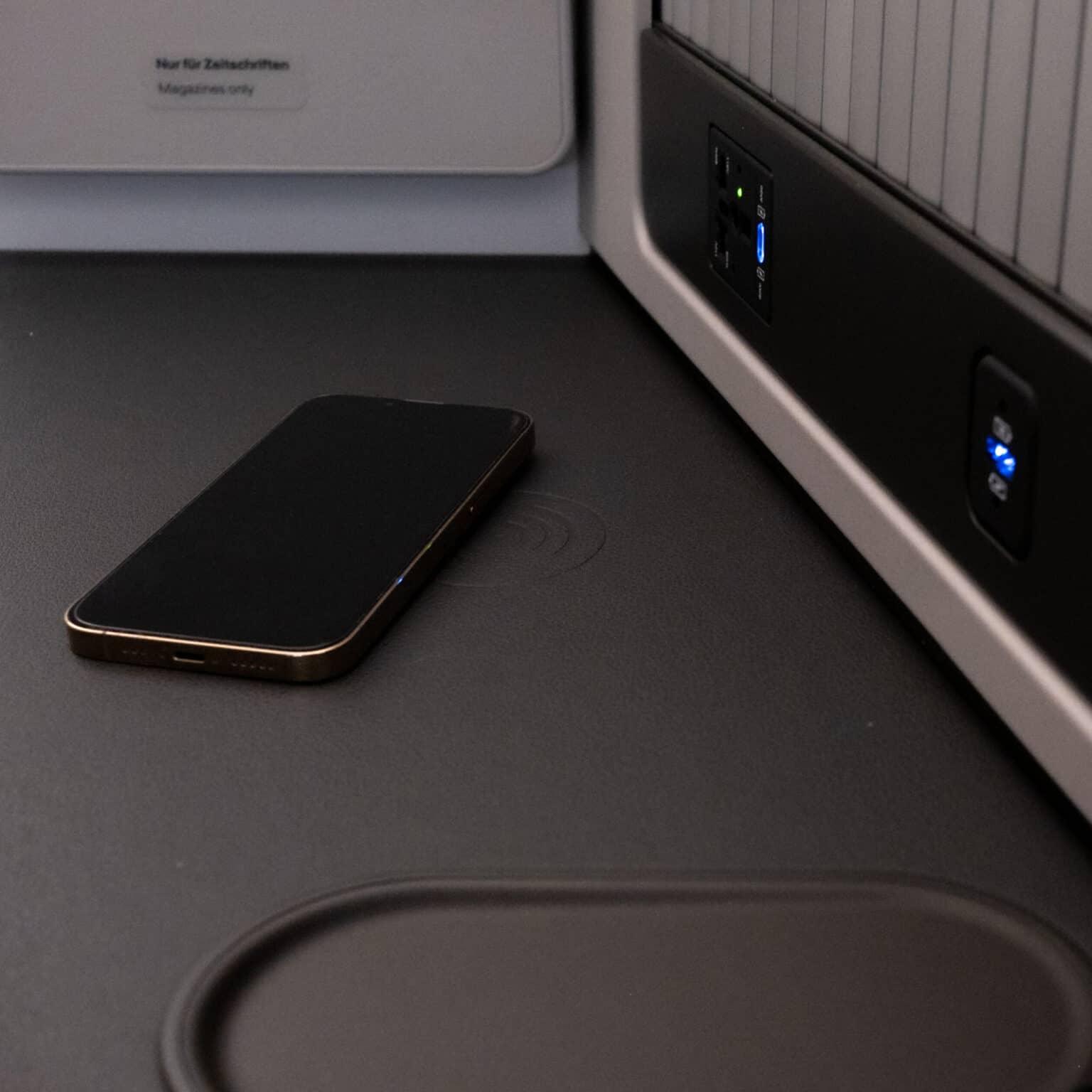 A wireless charging station with a phone directly next to the airplane seat.
