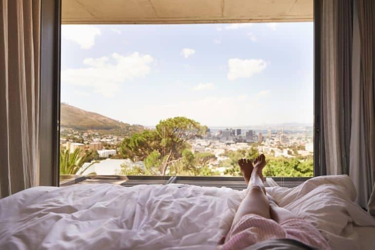 Woman lying in bed and looking at the view of nature in front of her.