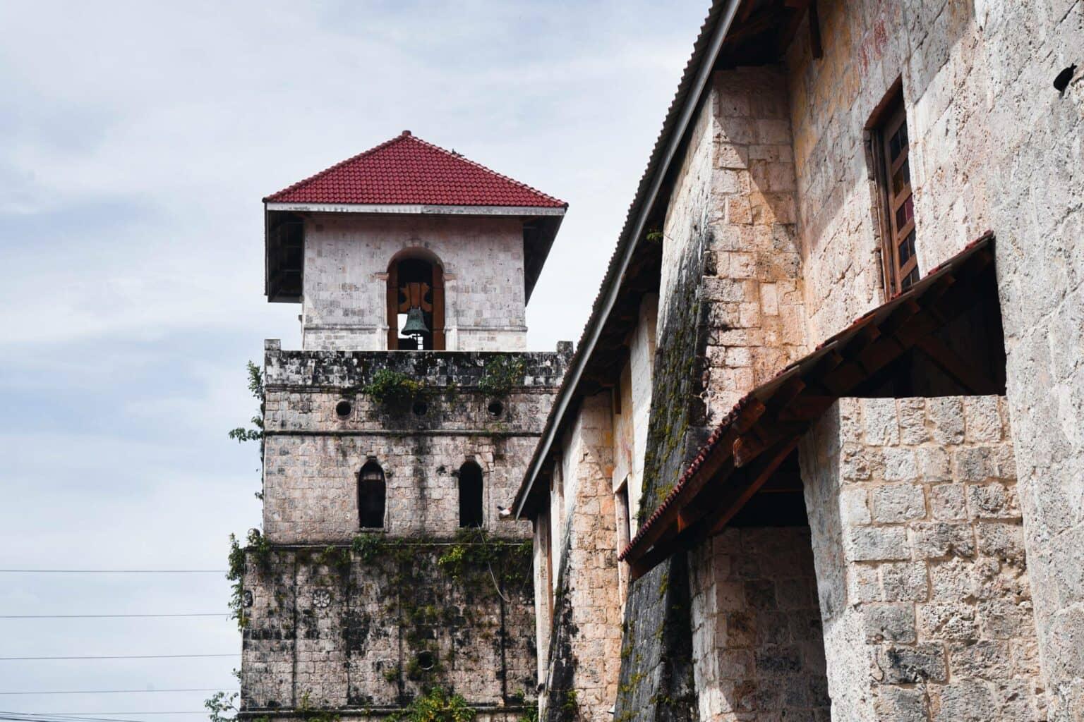 La torre de la iglesia de Baclayon en Bohol con campana y techo rojo es un importante lugar de interés en la isla filipina.