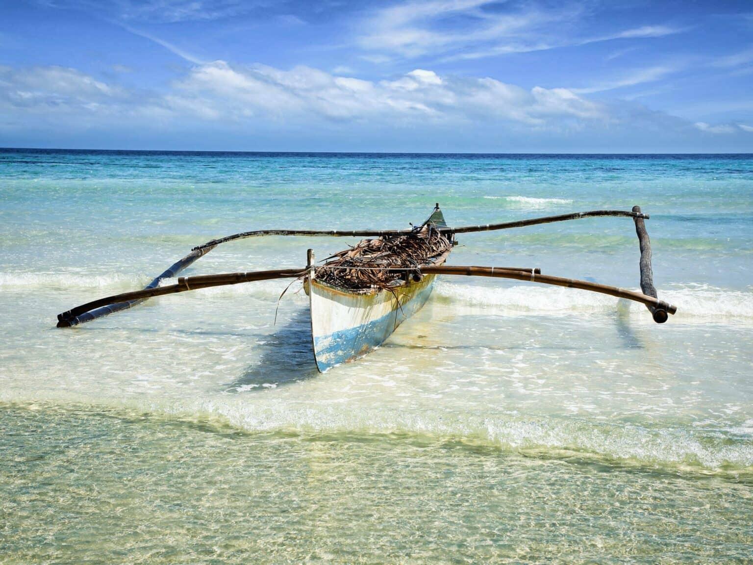 Una canoa antigua de madera está en la costa en el mar de Anda en la isla filipina de Bohol.