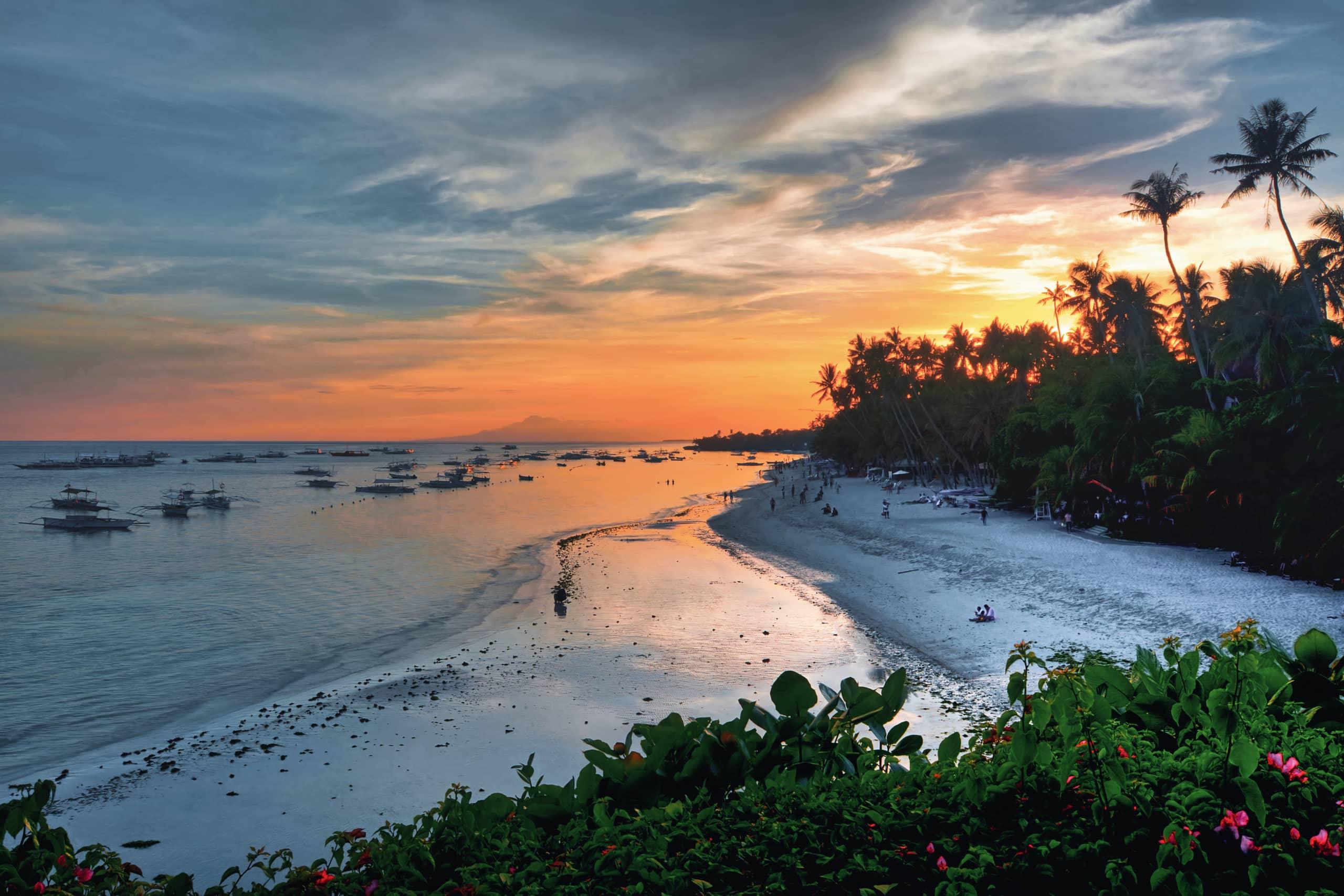 Una de las playas idílicas en Bohol con barcos al atardecer.