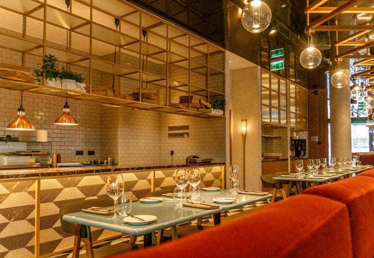 Comedor con una mesa puesta, al fondo se ve un bar.