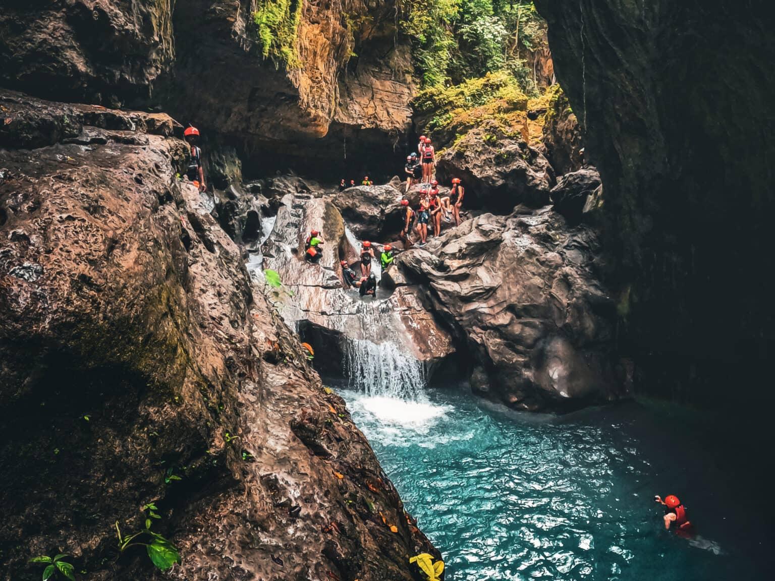 Personas con cascos rojos en una cascada dentro de la garganta.