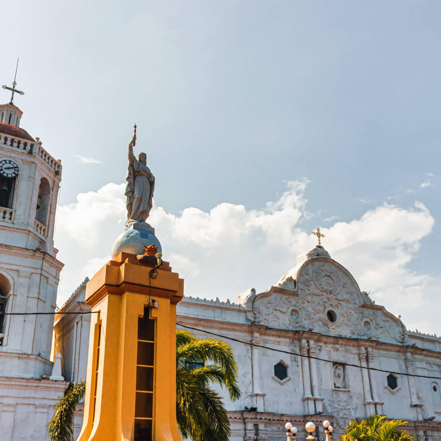 Una hermosa iglesia blanca se encuentra detrás de un monumento amarillo.