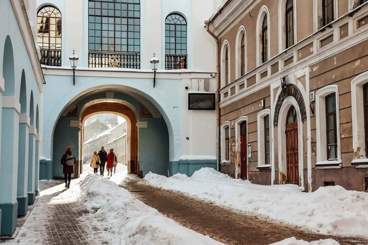 Personas caminando a través de la Puerta de la Mañana de Vilnius pintada de azul.