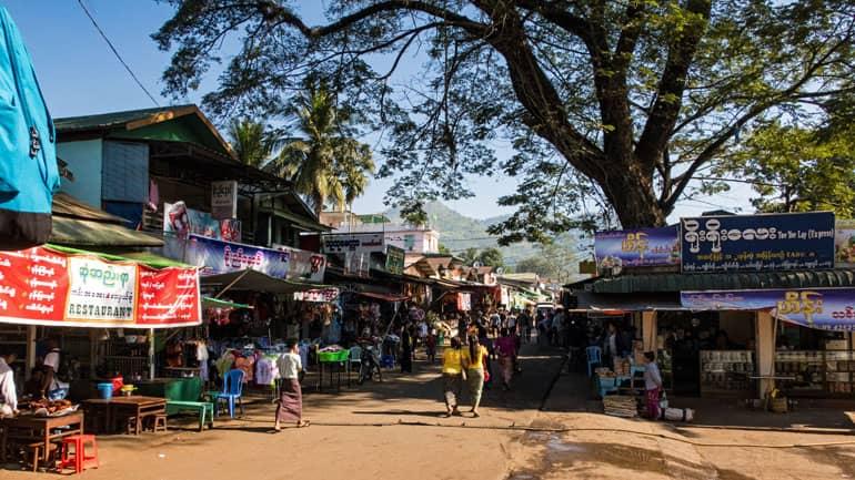 En el centro de Kinpun Sakhan, Myanmar, hay un bullicio con puestos de comida y personas.