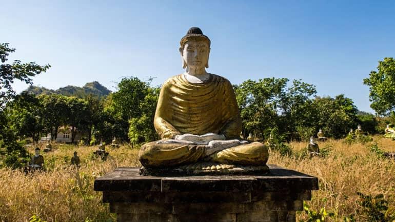 En Hpa An, Myanmar, hay una estatua de Buda sentado entre altos juncos y árboles en el Lumbini Buddha Garden.