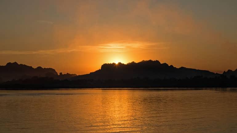 Atardecer rojizo detrás de las montañas en el lago Kan Thar Yar cerca de Hpa An en Myanmar.