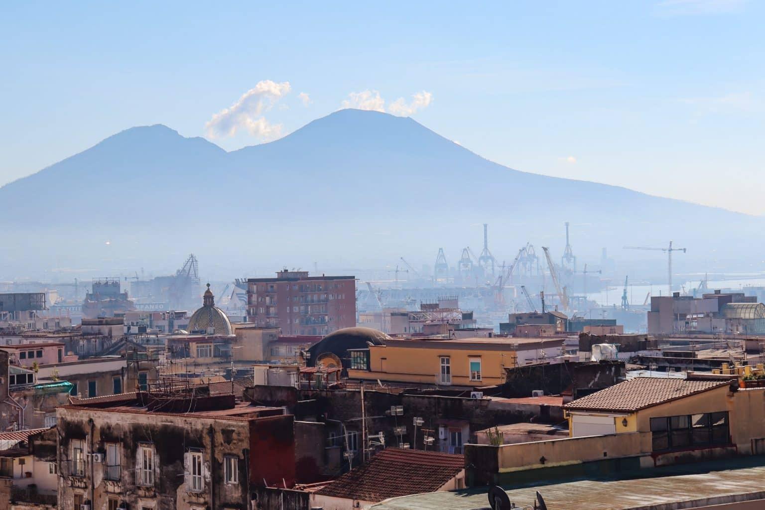 Mount Vesuvius looms behind the sandstone skyline of Naples in the fog.