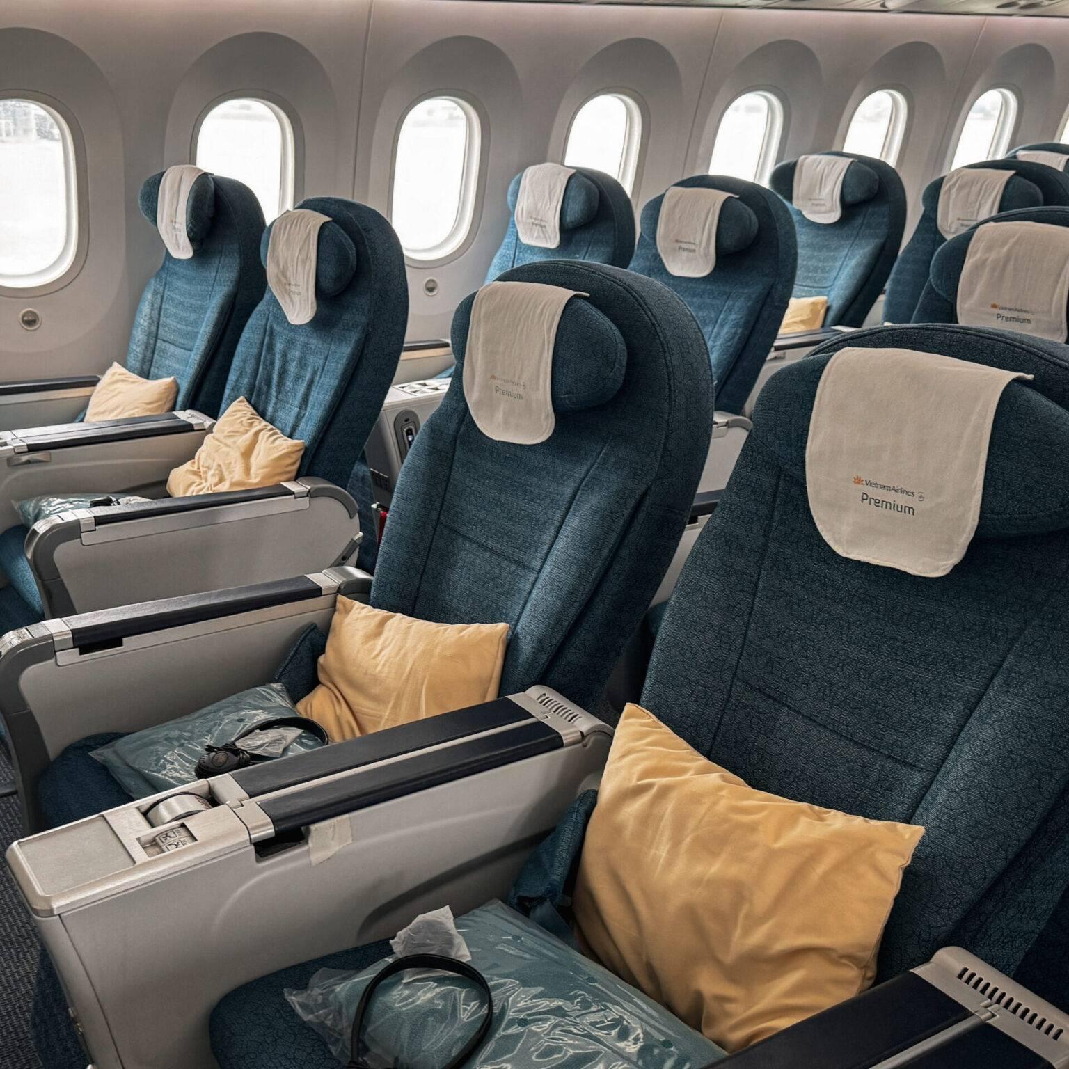 The cabin of Vietnam Airlines Premium Economy Class with blue seats and additional blankets and pillows.