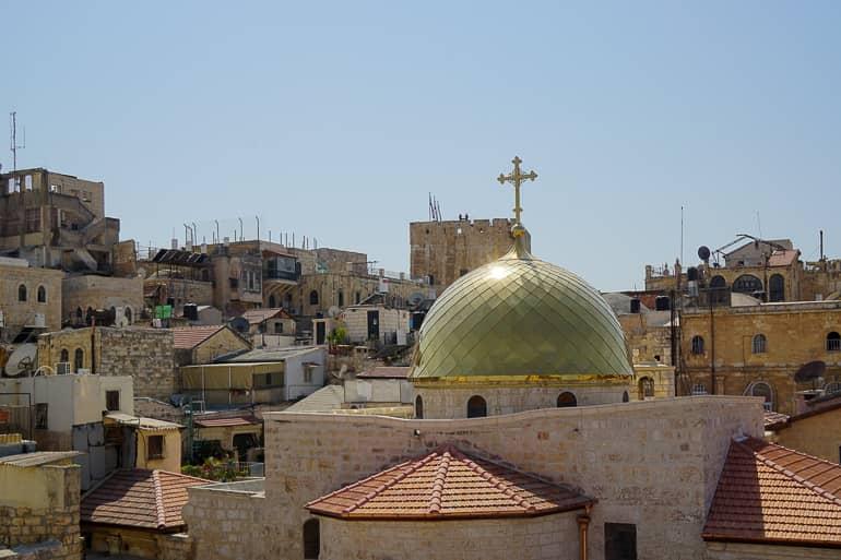El sol brilla sobre las paredes de piedra y una cúpula dorada de una iglesia católica en Jerusalén, Israel.