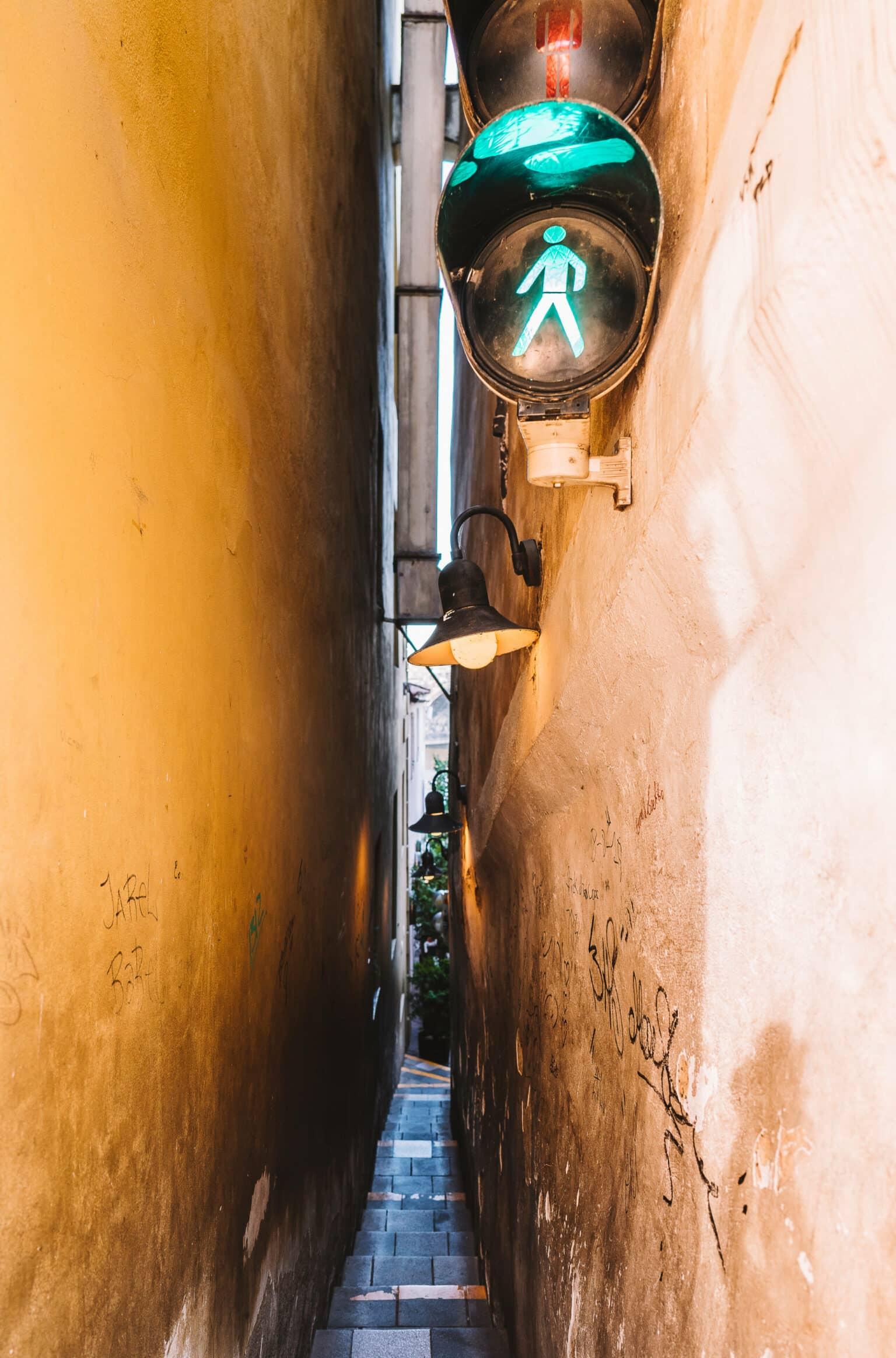A pedestrian traffic light in front of a very narrow alley in Prague.