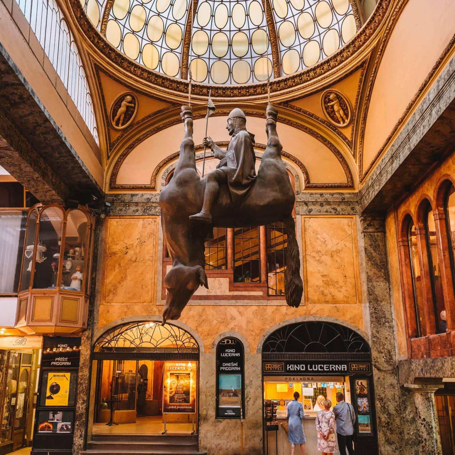 An upside-down horse with a rider on its belly forms the monument of the Wenceslas statue in the Lucerna Passage in Prague.