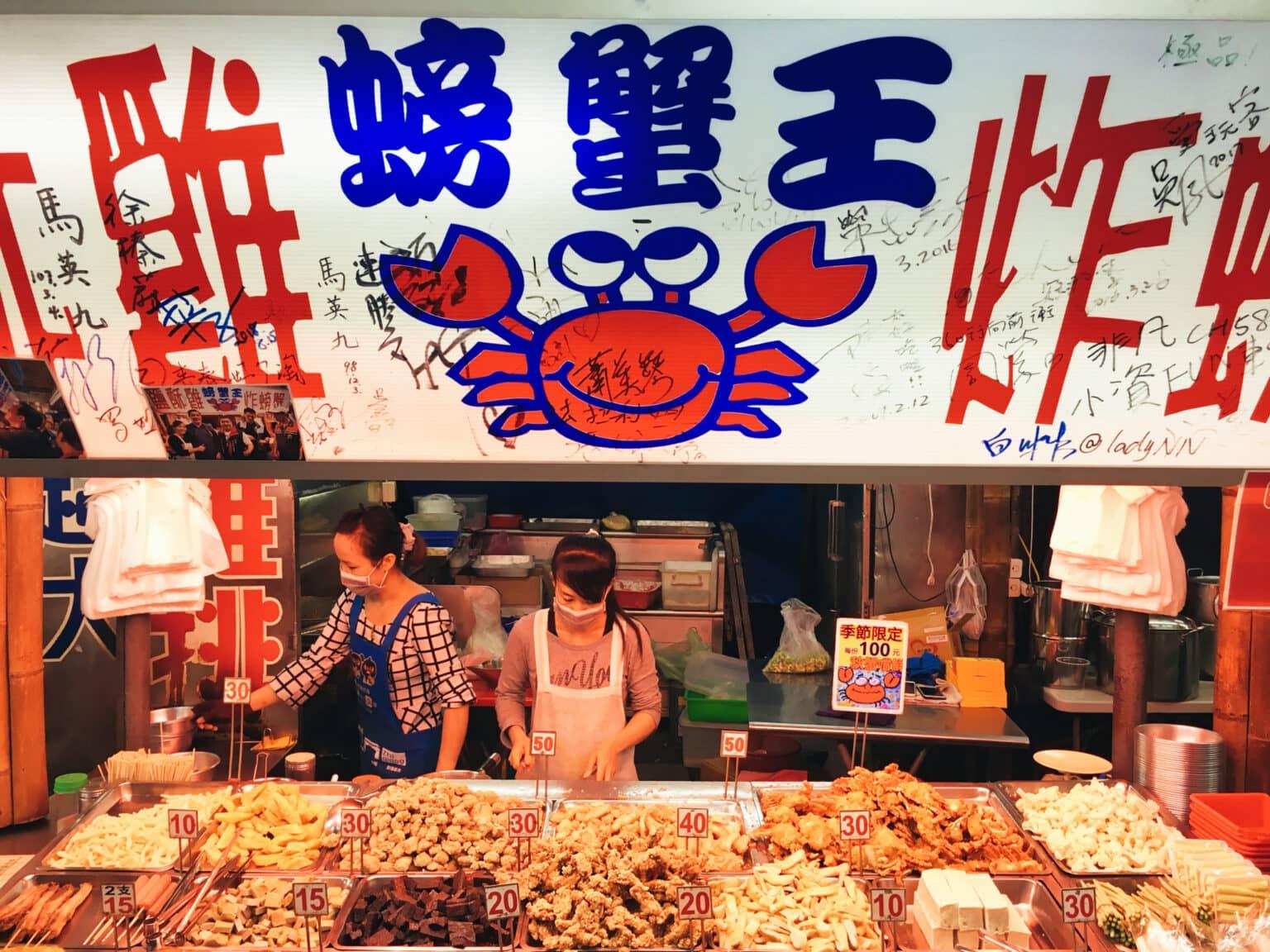 Two women stand behind a food stall at the Hualien Night Market in Taiwan.