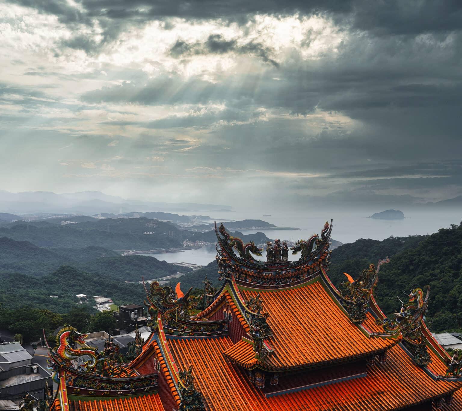 View from Jiufen over the red-roofed temple adorned with dragon sculptures towards Taiwan's northern coast.