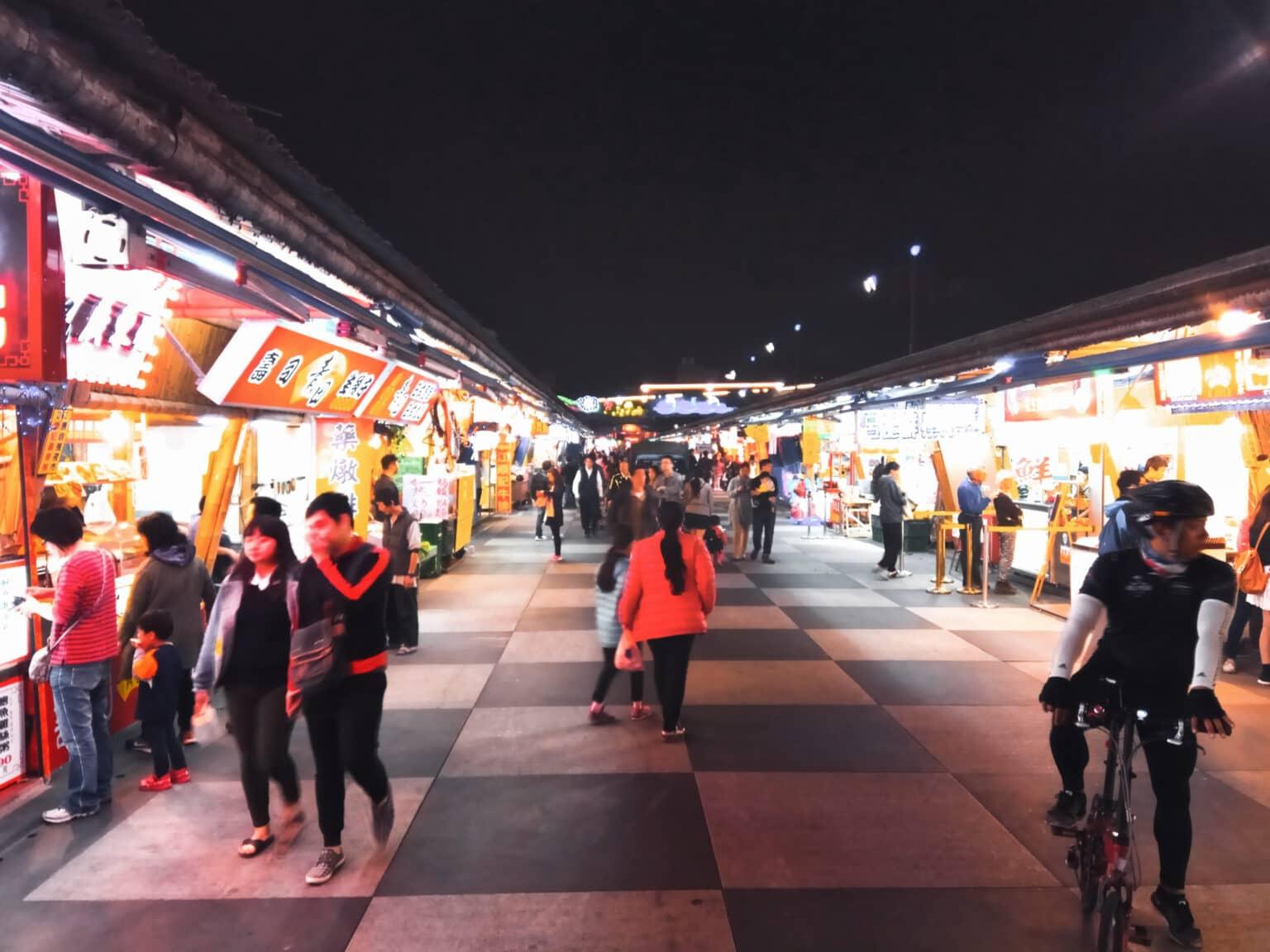 People stroll at night through the brightly lit Dongdamen Night Market in Taiwan.