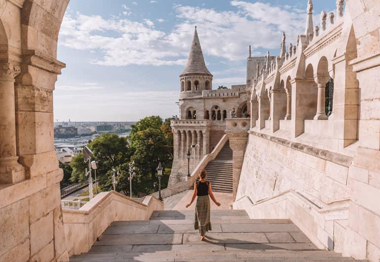 Viaje a Budapest: Una mujer bajando escaleras con un edificio al fondo.