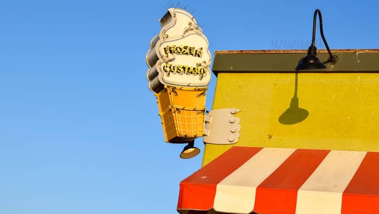 In Santa Monica, Los Angeles, a large ice cream cone is displayed as a sign on the yellow roof of an ice cream shop, with the usual red and white striped awning.